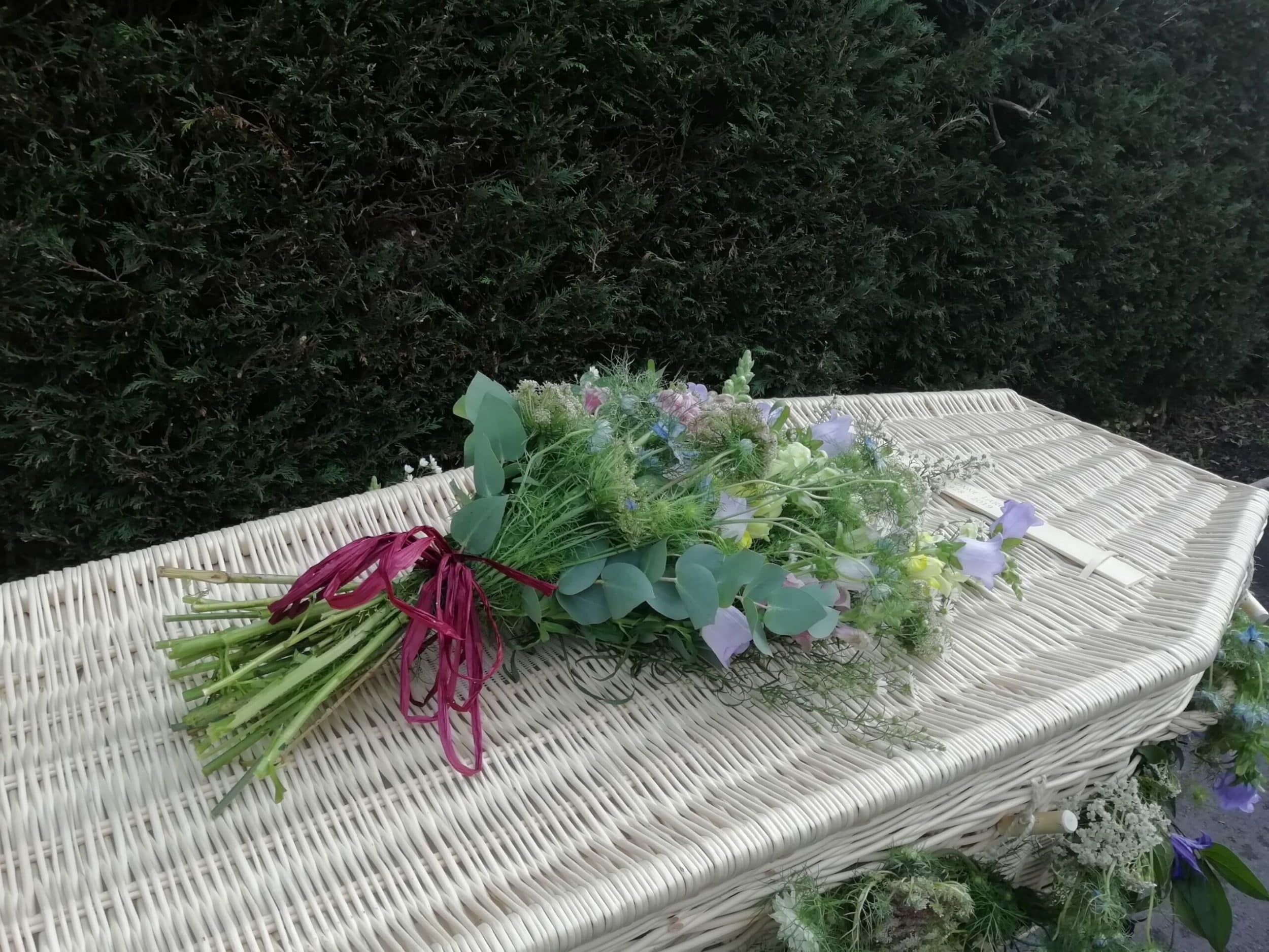 Wicker coffin with flowers on