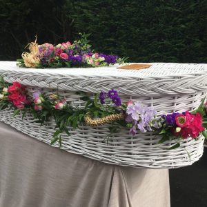 White wicker coffin with flowers