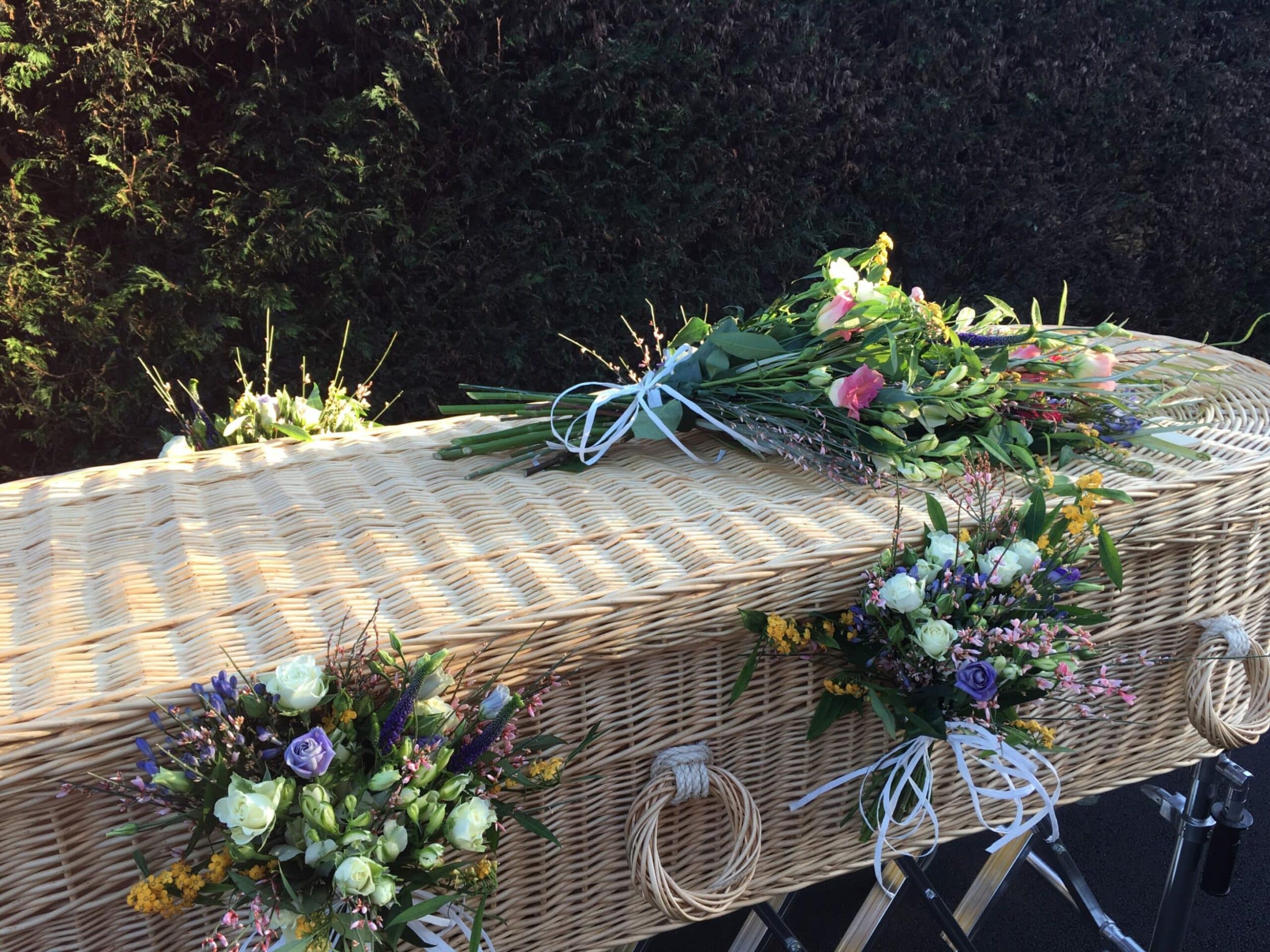 Wicker coffin with flowers on