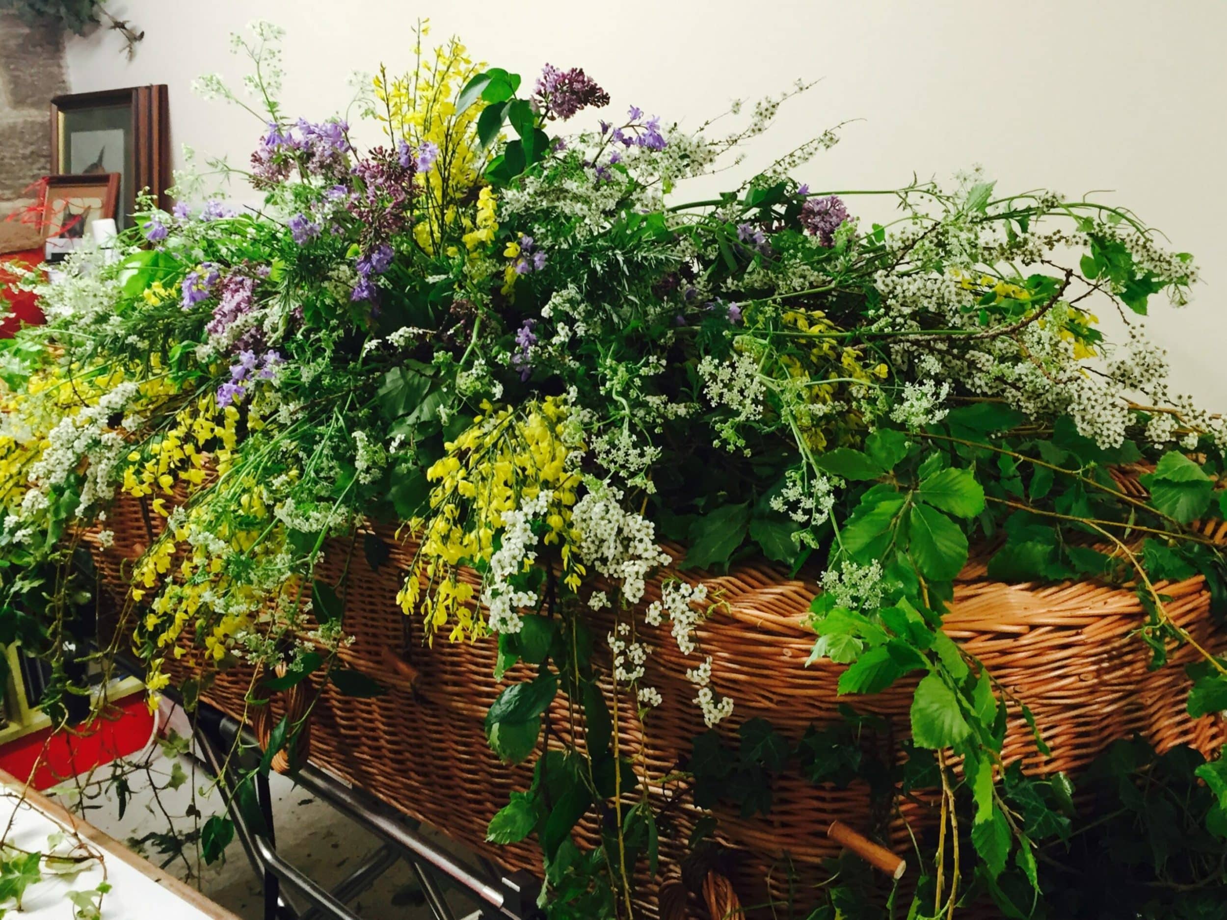 Wicker coffin with lots of flowers on